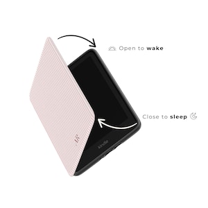 May include: A Kindle e-reader with a light pink cover featuring a white striped pattern. The cover is open, revealing the screen. The text "AR" is visible on the cover. The text "Open to wake" and "Close to sleep" are also visible.