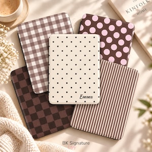 May include: Five rectangular e-reader cases featuring various patterns: a brown and white gingham check, a brown and pink polka dot, a cream case with small black dots and the name Emma, a dark brown checkerboard, and a brown and white vertical stripe.