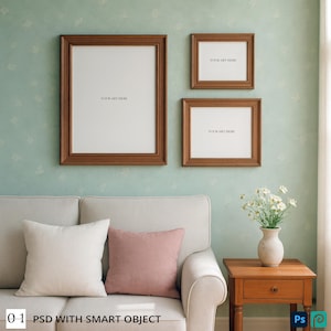 May include: Three brown framed art prints with the text "YOUR ART HERE" are displayed on a light green wall. A white sofa with two pillows, one white and one pink, sits below the artwork. A small wooden side table with a vase of flowers is to the right. The text "0.1 PSD WITH SMART OBJECT" is at the bottom.