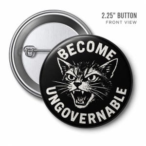 May include: A black 2.25-inch button with a silver pin back. The button features a white illustration of an angry cat with the words "BECOME UNGOVERNABLE" in a circular design around the cat's head.