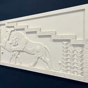 May include: White plaster relief sculpture depicting a stylized lion attacking a horse. The sculpture is framed with a decorative border and set against a plain white background.