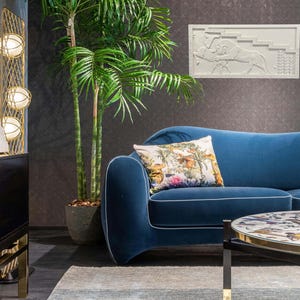 May include: A blue velvet sofa with a floral patterned pillow, a gold metal floor lamp with three white globe lights, and a round coffee table with a patterned top.