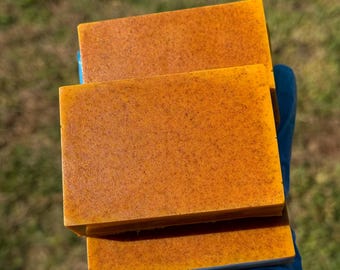 May include: Two bars of orange-coloured soap stacked on top of each other. The soap has a grainy texture.