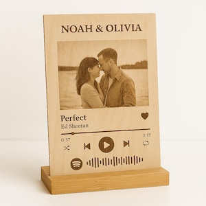 Könnte beinhalten: Eine Holzplakette mit einem Foto eines Paares, einer Musikplayer-Grafik und dem Text "NOAH & OLIVIA", "Perfect", "Ed Sheeran", "0:37", "3:17" und einem Spotify-Logo.