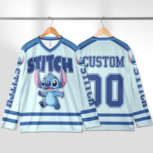 Puede incluir: Jersey de hockey azul claro y blanco con el personaje Stitch. La parte delantera de la camiseta tiene la palabra "STITCH" y una imagen de Stitch. La parte trasera de la camiseta tiene la palabra "CUSTOM" y el n&uacute;mero "00".