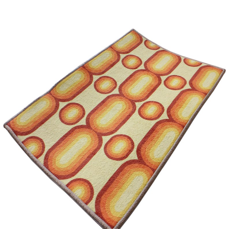 May include: A vintage style rug with a geometric pattern of orange and yellow circles and ovals on a cream background. The rug has a brown border.