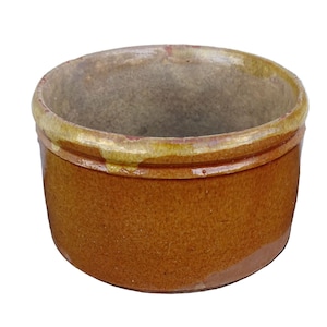 Op de afbeelding: Een kleine, ronde keramische pot met een getextureerde bruine buitenkant en een lichtere binnenkant. De rand is geaccentueerd met een gele en bruine glazuur. Deze rustieke container is geschikt voor keuken of decoratie.