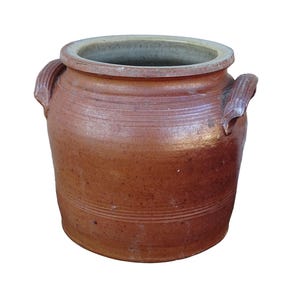 Op de afbeelding: Een bruine keramische pot met twee handvatten en een brede opening. De pot heeft een getextureerd oppervlak met horizontale lijnen in het midden. De binnenrand is lichter van kleur. Deze rustieke container is geschikt voor keuken of woondecoratie.