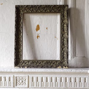 Op de afbeelding: Een rechthoekige fotolijst met een sierlijke, donker-metalen afwerking. De lijst is voorzien van ingewikkeld reliëfwerk, waaronder bloemmotieven en gestructureerde arceringen langs de rand, wat zorgt voor een gedetailleerd en decoratief uiterlijk.