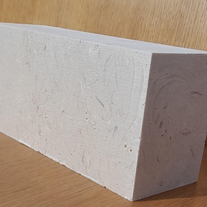 May include: A large, rectangular block of white plaster with a rough, textured surface. The plaster is slightly off-white in color and has a subtle sheen.