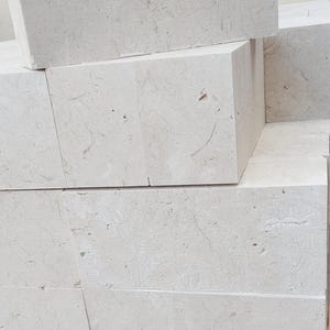 May include: Stack of light gray rectangular tiles with a rough, textured surface.