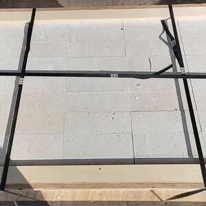 May include: A white ceramic tile sheet secured with black straps in a wooden crate.