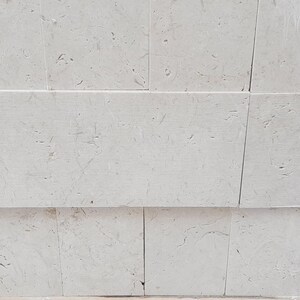 May include: A white wall with a tiled pattern. The tiles are arranged in a staggered pattern, creating a subtle visual texture.