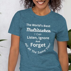 May include: A teal blue t-shirt with white text that reads "The World's Best Multitasker I Can Listen, Ignore And Forget All At The Same Time."