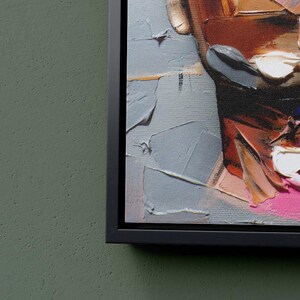 May include: Close-up of a colorful abstract painting with thick brushstrokes. The painting features shades of red, pink, white, and blue. The painting is framed in a black frame.