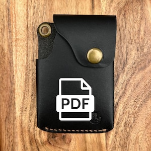May include: Black leather card holder with a flap secured by a brass snap. The front features a white PDF file icon. The holder has a stitched border and a brass rivet. The background is a wooden surface.
