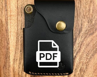 May include: Black leather card holder with a flap secured by a brass snap. The front features a white PDF file icon. The holder has a stitched border and a brass rivet. The background is a wooden surface.