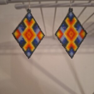May include: A pair of diamond-shaped earrings with a geometric pattern in shades of blue, orange, yellow, and black.