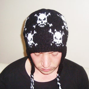 May include: Black knit beanie with white skull designs. The beanie has ear flaps and a long tassel.