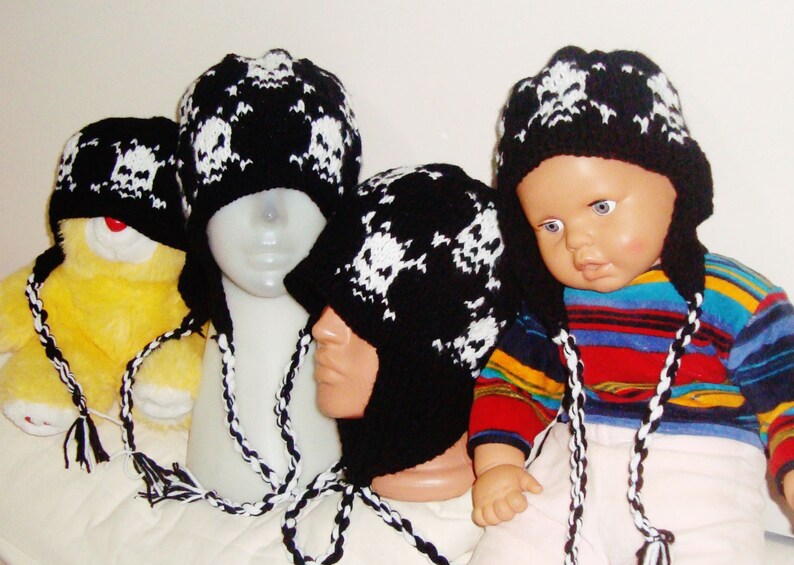 May include: Three black and white knit hats with skull designs. The hats have long ties that can be worn as ear warmers.