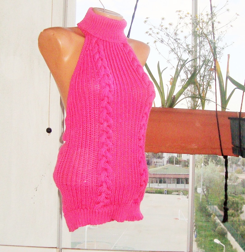 K&ouml;nnte beinhalten: Ein pinkfarbenes gestricktes Halstuch mit hohem Kragen und Zopfmuster.