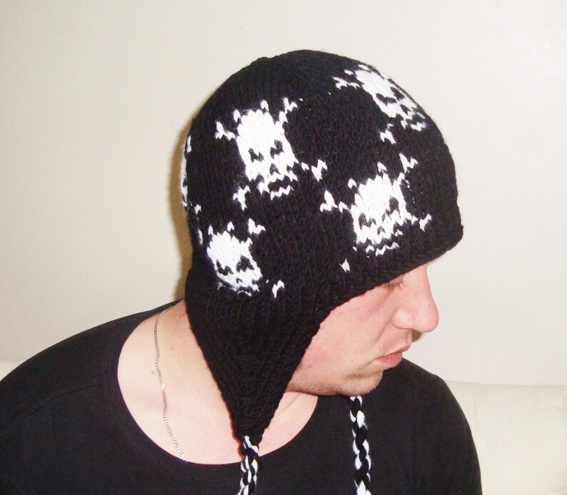 May include: Black knit beanie with a white skull pattern. The beanie has a long, dangling tail.
