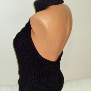 K&ouml;nnte beinhalten: Schwarzes gestricktes Halstuch mit breitem, schwarzem Choker-Ausschnitt. Das Oberteil ist &auml;rmellos und hat eine lockere, flie&szlig;ende Passform.