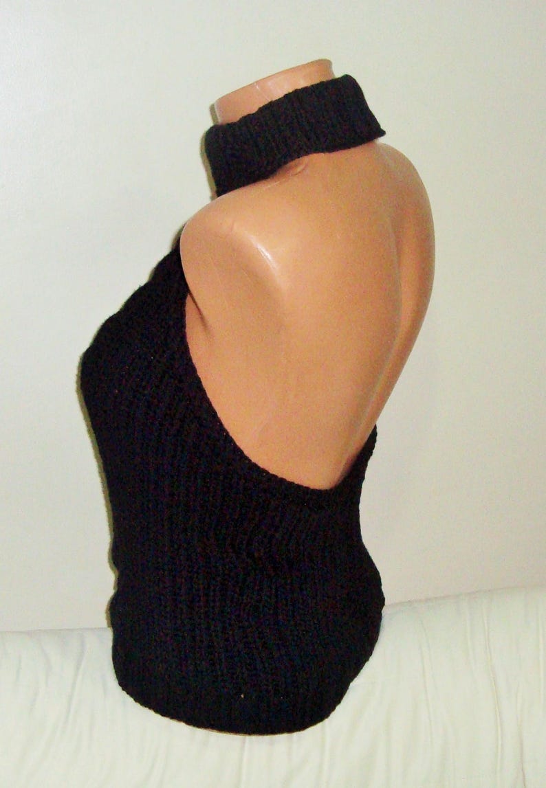 K&ouml;nnte beinhalten: Schwarzes gestricktes Halstuch mit breitem, schwarzem Choker-Ausschnitt. Das Oberteil ist &auml;rmellos und hat eine lockere, flie&szlig;ende Passform.
