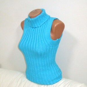 May include: A sleeveless, turquoise blue ribbed knit top with a turtleneck collar. The top is displayed on a mannequin, showcasing its form-fitting design. The ribbed texture adds visual interest to the garment.