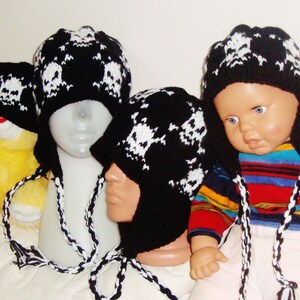 May include: Three black and white knit hats with skull designs. The hats have long ties that can be worn as ear warmers.