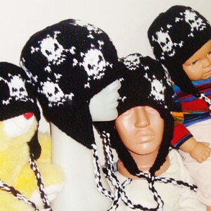 May include: Four black and white knit skull hats with long ties. The hats are on mannequins and a stuffed animal.