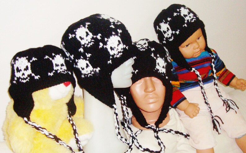 May include: Four black and white knit skull hats with long ties. The hats are on mannequins and a stuffed animal.