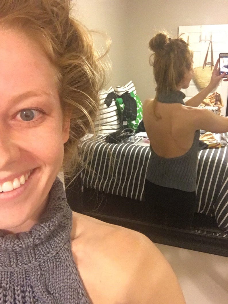 K&ouml;nnte beinhalten: Nahaufnahme einer Frau, die einen grauen Strickpullover mit Rollkragen tr&auml;gt. Der Pullover hat einen hohen Kragen und eine lockere Passform. Die Frau l&auml;chelt und schaut in die Kamera.