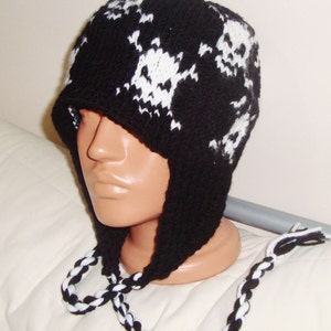 May include: Black and white knit skull hat with ear flaps and a matching braided cord.