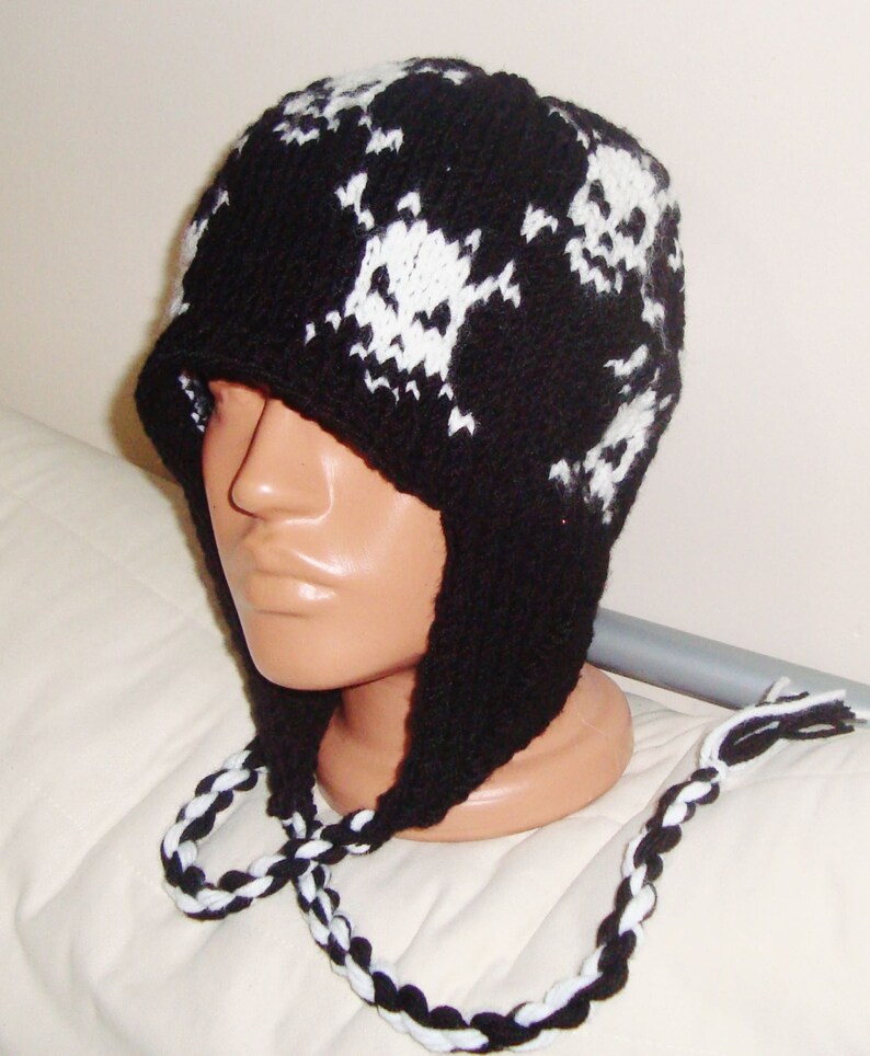 May include: Black and white knit skull hat with ear flaps and a matching braided cord.