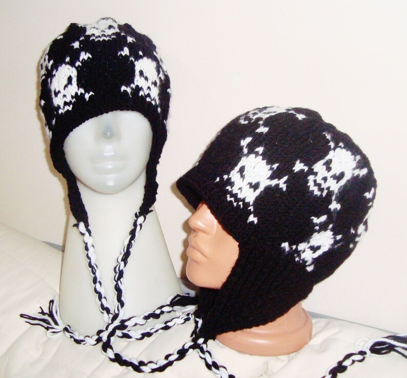 May include: Two black and white knit skull hats with long ties. One hat is a beanie style and the other is a slouchy hat with a flap that covers the ears.