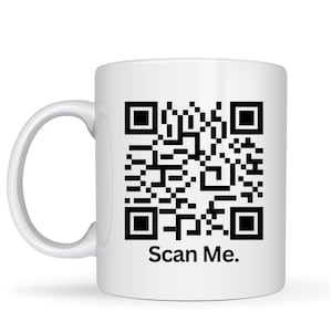 May include: White ceramic mug featuring a large black QR code and the text "Scan Me." The mug has a curved handle and a cylindrical shape. The design is simple and modern, suitable for everyday use.