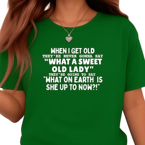 May include: A green t-shirt with white text. The text reads: "WHEN I GET OLD THEY'RE NEVER GONNA SAY 'WHAT A SWEET OLD LADY' THEY'RE GOING TO SAY 'WHAT ON EARTH IS SHE UP TO NOW?!'"