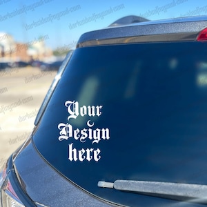 May include: A black car with a white vinyl sticker on the back window. The sticker says "Your Design Here" in a gothic font.