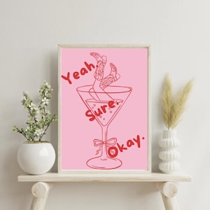 Pode incluir: Impressão de arte imprimível rosa com um desenho de linha vermelha de uma taça de martini com pernas em botas de cowboy dentro. O texto "Yeah Sure Okay." está escrito em vermelho ao redor do copo.