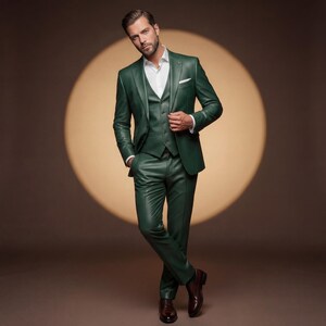 May include: A three-piece, emerald green suit with a white dress shirt. The suit includes a jacket, vest, and trousers. The man is wearing brown leather dress shoes. The background is a warm brown with a circular spotlight.
