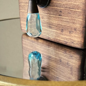 Peut inclure: Un bouton de cabinet en cristal bleu avec une base en bronze. Le bouton est fix&eacute; &agrave; une porte de cabinet en bois.