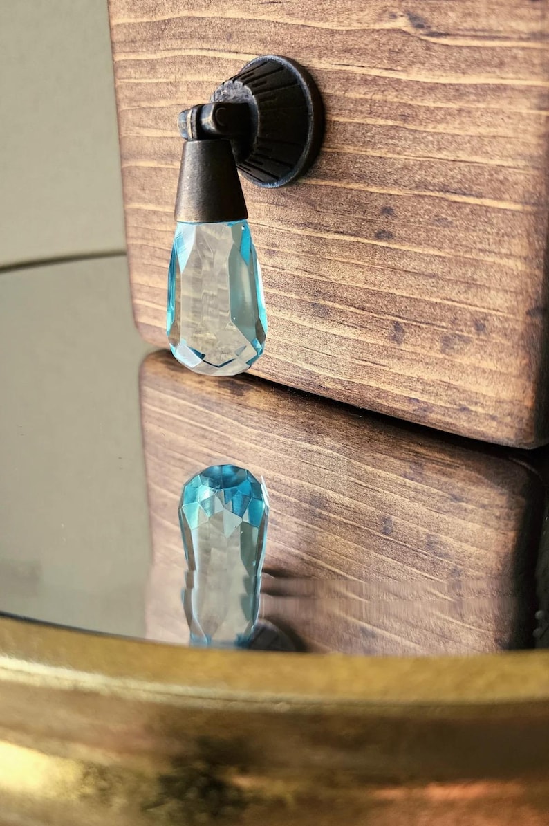 Peut inclure: Un bouton de cabinet en cristal bleu avec une base en bronze. Le bouton est fix&eacute; &agrave; une porte de cabinet en bois.