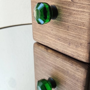 Op de afbeelding: Twee houten laden met groene glazen knoppen. De laden zijn op elkaar gestapeld.
