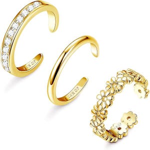 May include: Three gold-toned open rings with the stamp 14K GF. One ring features a channel-set row of clear stones, one is a plain polished band, and one is designed with a series of connected daisy flower shapes along the entire outer surface.