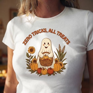 May include: A white short-sleeve t-shirt featuring a graphic of a smiling ghost holding a basket of pumpkins. The text "ZERO TRICKS, ALL TREATS" is printed in orange above the ghost, surrounded by sunflowers, corn stalks, and pumpkins.