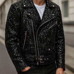 May include: Black sequin biker jacket with silver zippers and a belt. The jacket has a classic asymmetrical design with a notched collar and a fitted silhouette. The sequins add a touch of glamour to the outerwear.