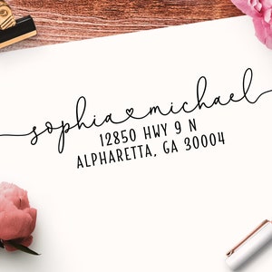 May include: A white card with black calligraphy that reads "sophia♡michael" and the address "12850 HWY 9 N ALPHARETT, GA 30004".