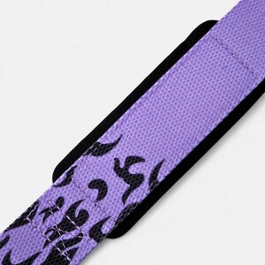 Close-up of purple wrist wraps showing double-stitched construction and black flame artwork. Durable anime workout gear designed for powerlifting and crossfit training.