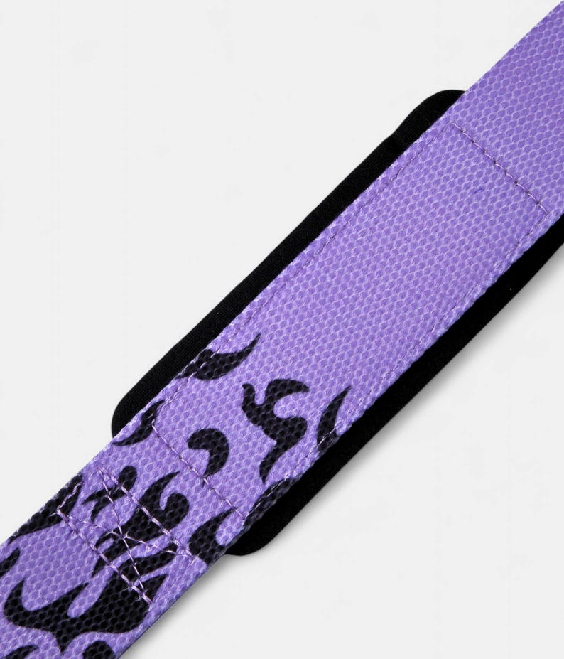 Close-up of purple wrist wraps showing double-stitched construction and black flame artwork. Durable anime workout gear designed for powerlifting and crossfit training.